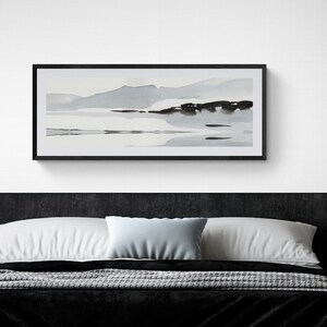 May include: A rectangular framed watercolour landscape painting in grey and black tones hangs above a black bed. The artwork depicts a minimalist scene of mountains and water, creating a serene and modern aesthetic. The room features a neutral colour palette.