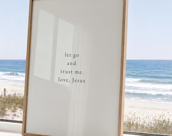 May include: A rectangular wall art print in a light wood frame featuring a white background with black text that reads: let go and trust me. love, Jesus. The print is positioned upright, displaying a clean, minimalist aesthetic with clear lettering.