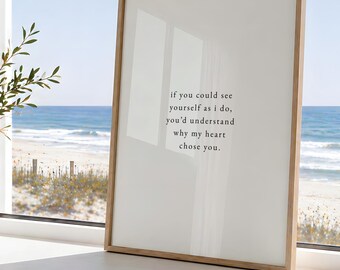 May include: A rectangular framed print with a light-colored background and black text that reads: if you could see yourself as i do, you'd understand why my heart chose you. The frame is made of light-toned wood and has a clean, simple design.