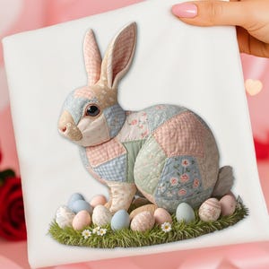 以下が含まれることがあります： パステルカラーのパッチワークデザインの装飾的なイースターバニー。バニーは緑の草の上に描かれた卵に囲まれています。バニーの耳は直立しており、目は暗いです。