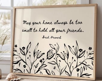 May include: A framed wall art print featuring a light beige background with black ink-style botanical illustrations at the bottom and the text: May your home always be too small to hold all your friends. Irish Proverb, written in black script.