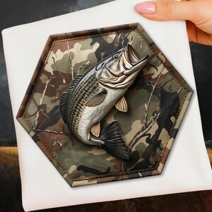 May include: A detailed, metallic fish sculpture with an open mouth, mounted on a camouflage hexagonal base. The fish has a silver body with dark stripes and gold-colored fins. The base is a mix of green, brown, and tan, with a stitched border.