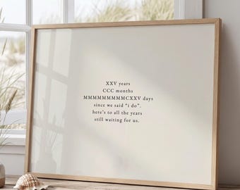 May include: A framed print featuring black text on a light beige background. The text reads: XXV years, CCC months, MMMMMMMMMMCXXV days since we said "i do". here's to all the years still waiting for us. The frame is a light-colored wood.