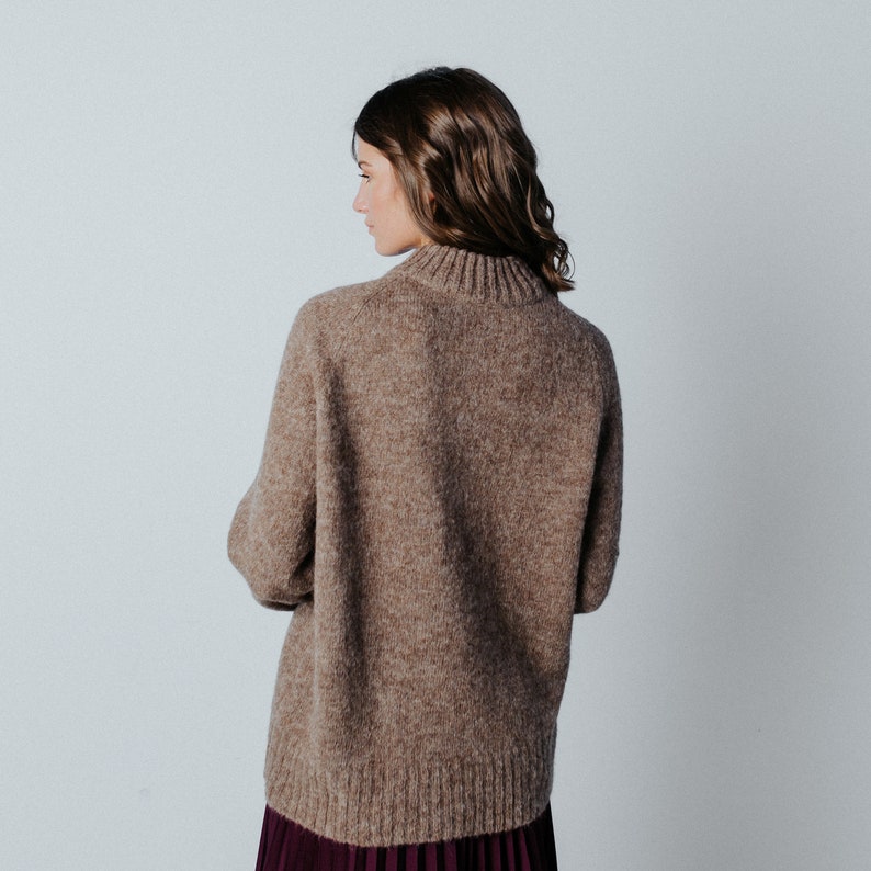 May include: A brown, fuzzy sweater with a high neck and long sleeves.