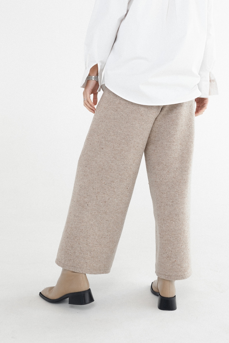 May include: Beige wide-leg pants with a speckled texture. The pants are made of a soft, comfortable fabric and have a relaxed fit.