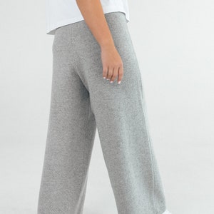 May include: Gray wide-leg pants made from a soft knit fabric. The pants have a relaxed fit and a straight leg.