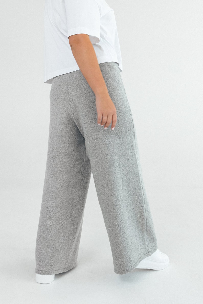 May include: Gray wide-leg pants made from a soft knit fabric. The pants have a relaxed fit and a straight leg.