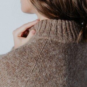 May include: Close-up of a brown knitted sweater with a high neck.