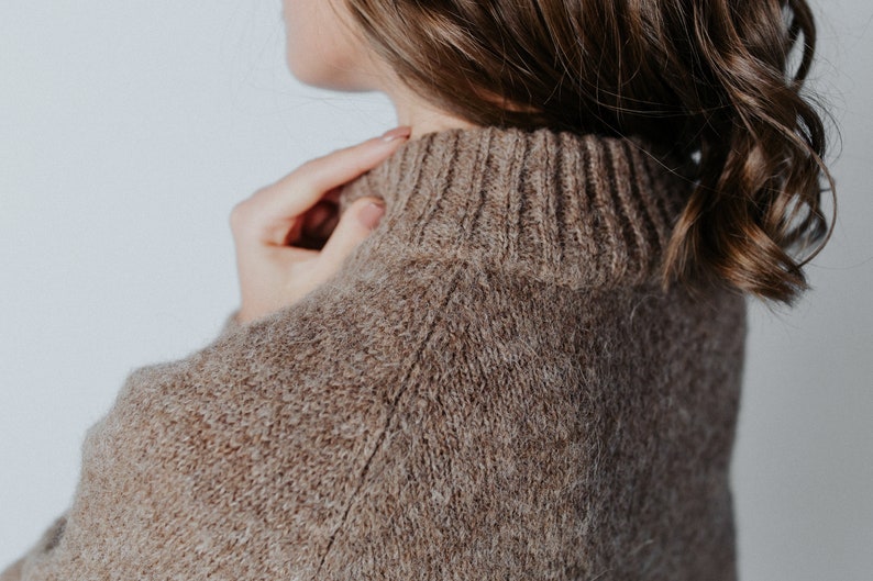May include: Close-up of a brown knitted sweater with a high neck.