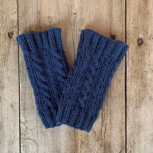 May include: A pair of navy blue knitted leg warmers with a cable knit design. The leg warmers are made of a soft, textured yarn and are designed to keep the legs warm. The leg warmers are approximately 12 inches long.