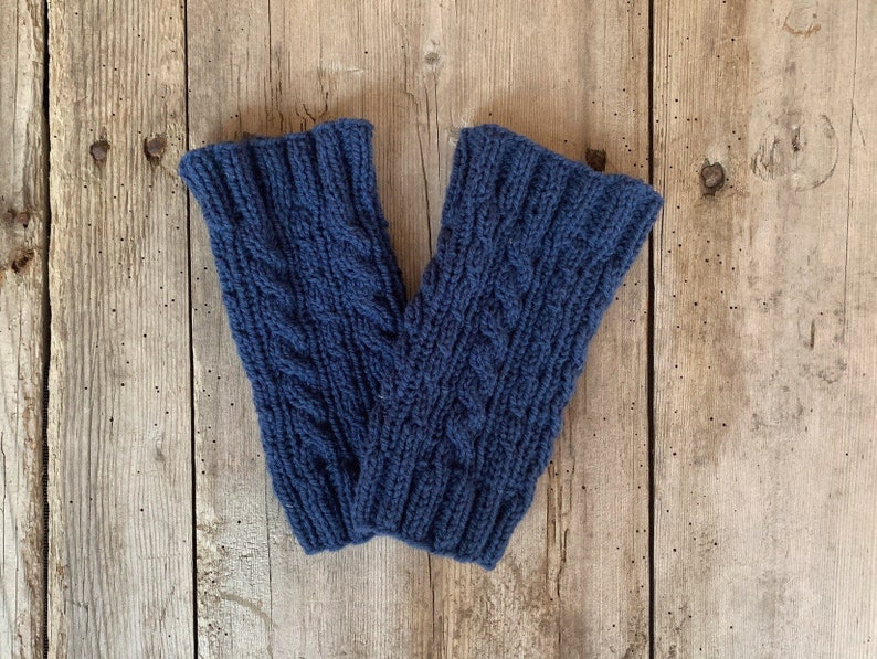 May include: A pair of navy blue knitted leg warmers with a cable knit design. The leg warmers are made of a soft, textured yarn and are designed to keep the legs warm. The leg warmers are approximately 12 inches long.