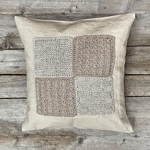 Könnte beinhalten: Ein beigefarbenes Leinenkissen mit vier quadratischen Flecken aus gestricktem Stoff in einem Farbton von Hellbraun und Beige.