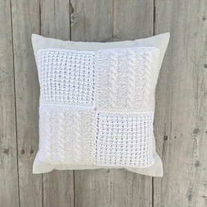 Könnte beinhalten: Ein weißes Häkelkissen mit quadratischem Patchwork-Muster. Das Kissen ist aus einem weichen, strukturierten Stoff gefertigt und hat einen dezenten Glanz.