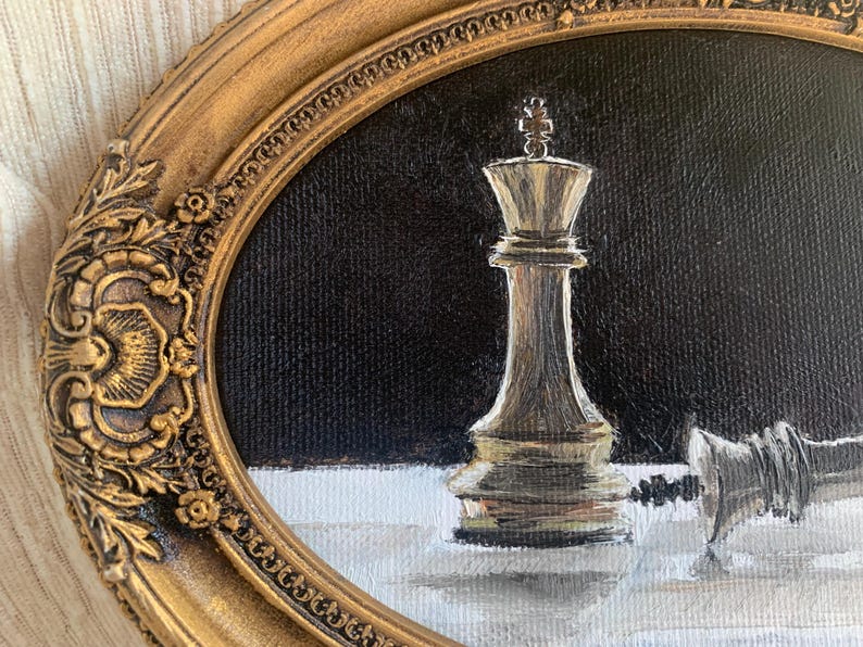 May include: An oil painting in an ornate oval gold frame depicting a vertical chess king piece standing on a white surface against a black background, with a second chess piece lying horizontally on its side next to the upright king piece.