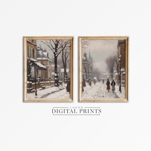 Puede incluir: Dos pinturas enmarcadas que representan una escena de calle nevada en una ciudad europea. Las pinturas están en un marco de madera claro con un acabado dorado. Las pinturas están colgadas en una pared blanca.