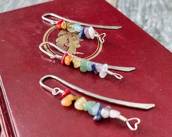 May include: Three silver bookmark pendants with rainbow colored gemstone beads. Each bookmark has a heart-shaped charm at the end.