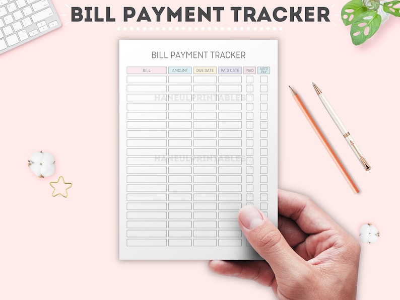 May include: A white bill payment tracker with pastel-colored headers, held by a hand. The tracker includes columns for bill, amount, due date, paid date, and auto-pay. The text "BILL PAYMENT TRACKER" is at the top.