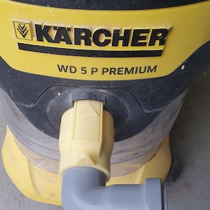Könnte beinhalten: Ein gelb-schwarzer Kärcher WD 5 P PREMIUM Staubsauger mit einem grauen Winkelrohr. Der Staubsauger hat das Kärcher-Logo und Produktinformationen aufgedruckt.