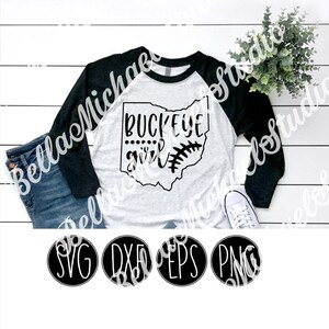 May include: A white and black baseball raglan t-shirt with the text "Buckeye girl" and an outline of the state of Ohio with a baseball stitch design. The shirt is on a white wooden surface with a pair of blue jeans and a potted plant. The image also includes four black circles with the text "SVG", "DXF", "EPS", and "PNG" in white.
