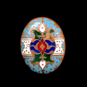 May include: A round, oval-shaped button with a blue, green, red, and white enamel design. The button has a copper-colored base.