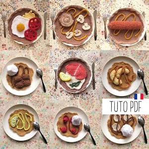 Peut inclure: Neuf assiettes en crochet avec différents motifs alimentaires, dont un œuf au plat, une saucisse, un poisson, un croissant et une fraise. Les assiettes sont sur un fond blanc avec un motif coloré.