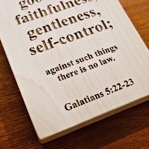 May include: A rectangular wooden plaque with engraved text. The text includes the words "goodness, faithfulness, gentleness, self-control" and a Bible verse reference. The plaque is light-colored.