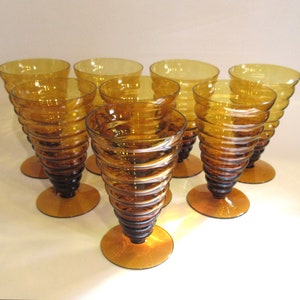 May include: Set of eight amber glass drinking glasses with a spiral design. The glasses are clear and have a textured surface.