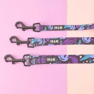 May include: Three black dog leashes with purple, blue, and white abstract patterns. Each leash has a black metal clip and a black label with the text "EM & ME" printed in white.