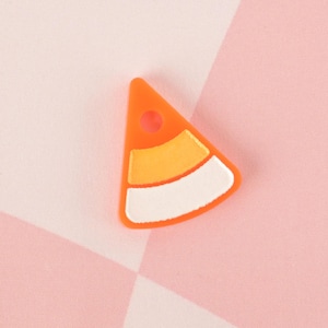 May include: Orange, yellow, and white candy corn charm in the shape of a triangle.
