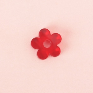 Può includere: Un fiore di plastica rosso con un foro al centro. Il fiore ha sei petali ed è un design semplice.