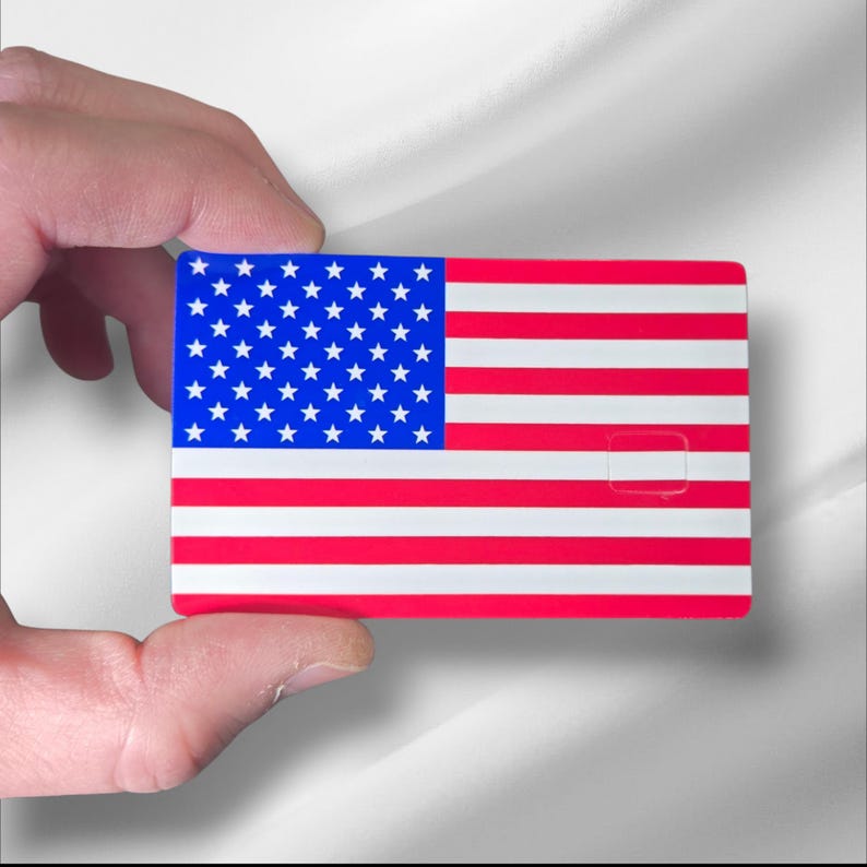 Pu&ograve; includere: Una carta rettangolare con il design della bandiera americana. La carta ha un campo blu con stelle bianche nell'angolo in alto a sinistra e strisce rosse e bianche a destra. Un piccolo ritaglio rettangolare &egrave; visibile sul lato destro.