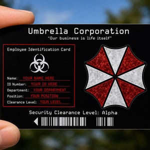 以下が含まれることがあります： Umbrella Corporationのロゴ、バイオハザードマーク、「Our business is life itself」というテキストが記載された黒い長方形のプラスチック製身分証明書。名前、ID番号、部署、役職、クリアランスレベルを記入する欄があります。