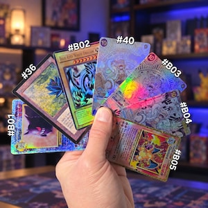 May include: A collection of six rectangular trading cards held in a fan shape. The cards feature various characters and creatures with holographic finishes, including Blue-Eyes White Dragon, Gengar, and Charizard, labelled with codes #B01, #B02, #B03, #B04, #B05, #36, and #40.