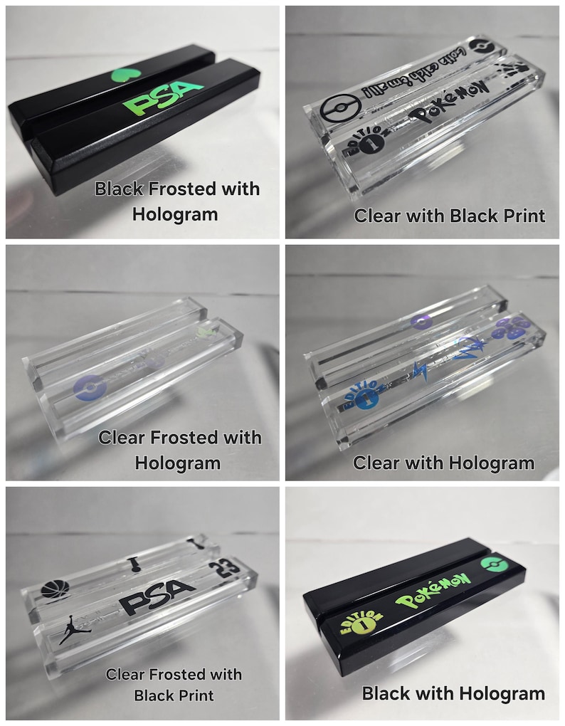 May include: Six different acrylic display stands for trading cards. The stands are clear, frosted, and black with holographic and black printed designs. The stands feature the text "PSA" and "Pokemon".