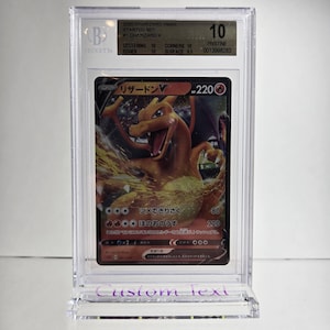 Puede incluir: Una tarjeta coleccionable Charizard VMAX calificada del Starter Set 2020, dentro de un soporte protector transparente. La tarjeta presenta una ilustraci&oacute;n de drag&oacute;n naranja llameante y texto japon&eacute;s. El soporte est&aacute; calificado con un 10 por Beckett.