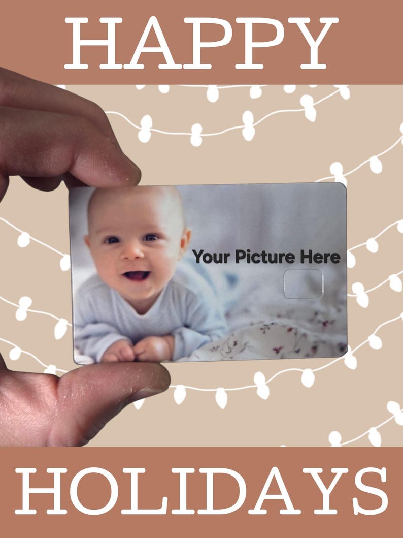 May include: A card held by a hand, featuring a baby's photo and the text "Your Picture Here." The card is set against a festive background with the words "HAPPY HOLIDAYS" in white, and string lights.