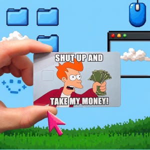 May include: A rectangular credit card skin featuring a cartoon character with orange hair and a red shirt holding a stack of green cash. The text SHUT UP AND TAKE MY MONEY is printed in white capital letters against a light grey background.