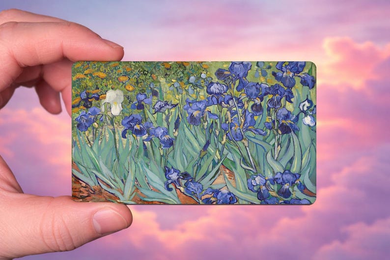 May include: A rectangular art print featuring a painting of blue irises in a field. The artwork has a vibrant color palette with shades of blue, green, yellow, and brown. The print is held against a backdrop of a pink and purple sky.