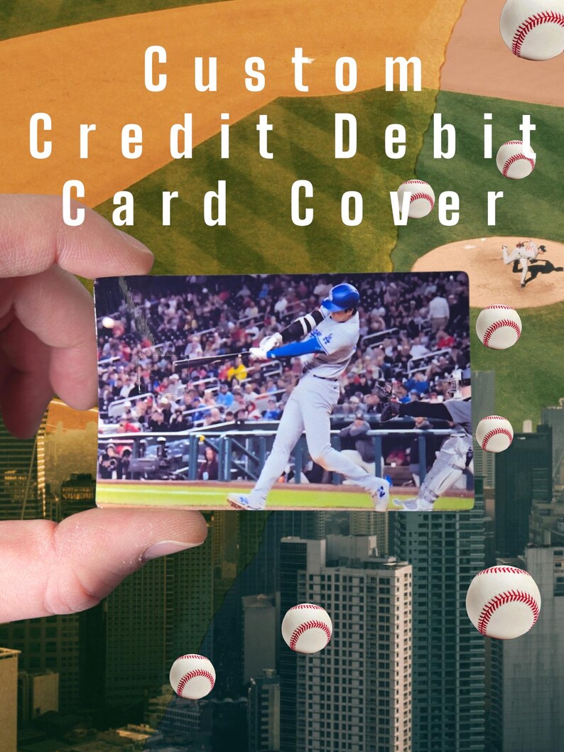 May include: A custom credit/debit card cover featuring a baseball player mid-swing, set against a stadium crowd. The background includes baseballs and a cityscape. Text on the card reads "Custom Credit Debit Card Cover."