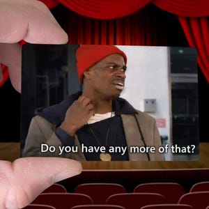 May include: A meme featuring a man in a red beanie and a brown jacket, with the text "Do you have any more of that?" The image is held by a hand against a backdrop of a theater stage with red curtains.