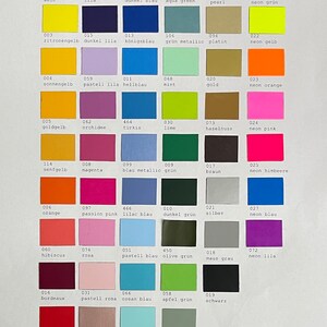 Puede incluir: Una carta de colores titulada Folienfarben que muestra una cuadr&iacute;cula de numerosas muestras rectangulares de vinilo adhesivo en varios tonos, incluyendo blanco, amarillo, naranja, rosa, rojo, morado, azul, verde, marr&oacute;n, gris y negro, cada una con n&uacute;mero y nombre.