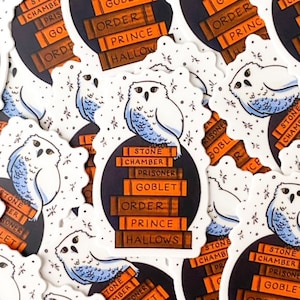 May include: A set of Harry Potter book stickers featuring a white owl with blue markings and a stack of books with the titles of each book in the series. The titles include "Harry Potter and the Sorcerer's Stone", "Harry Potter and the Chamber of Secrets", "Harry Potter and the Prisoner of Azkaban", "Harry Potter and the Goblet of Fire", "Harry Potter and the Order of the Phoenix", "Harry Potter and the Half-Blood Prince", and "Harry Potter and the Deathly Hallows".