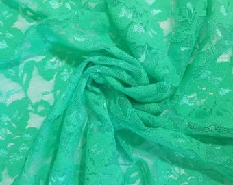 May include: A close-up of a bright green lace fabric with a floral pattern. The fabric is soft and delicate, and it would be perfect for a variety of crafting projects.