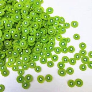May include: A large pile of green and white kiwi fruit slices, scattered on a white background. The kiwi slices are made of polymer clay and are perfect for crafting and decorating.