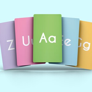 May include: Five colorful cards with letters of the alphabet printed on them. The cards are arranged in a semi-circle with the green card with the letters "Aa" in the center. The cards are purple, pink, green, blue, and yellow.