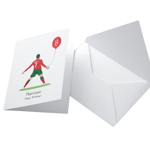 May include: A white card with a red and green illustration of a soccer player holding a red balloon with the number 8 on it. The text "Harrison Happy Birthday!" is printed on the card.