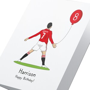 Puede incluir: Una tarjeta de cumplea&ntilde;os con una ilustraci&oacute;n de dibujos animados de un jugador de f&uacute;tbol que lleva una camiseta roja y blanca con el n&uacute;mero 7 y el nombre "RONALDO" en la espalda. El jugador sostiene un globo rojo con el n&uacute;mero 8. La tarjeta dice "Harrison &iexcl;Feliz cumplea&ntilde;os!" en la parte inferior.