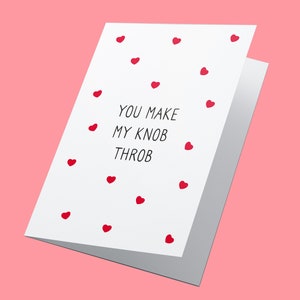 Op de afbeelding: Een witte wenskaart met de tekst "YOU MAKE MY KNOB THROB" in het zwart, omringd door kleine rode hartjes. De kaart is open, waardoor de binnenkant zichtbaar is, tegen een roze achtergrond. Een romantisch en speels ontwerp.