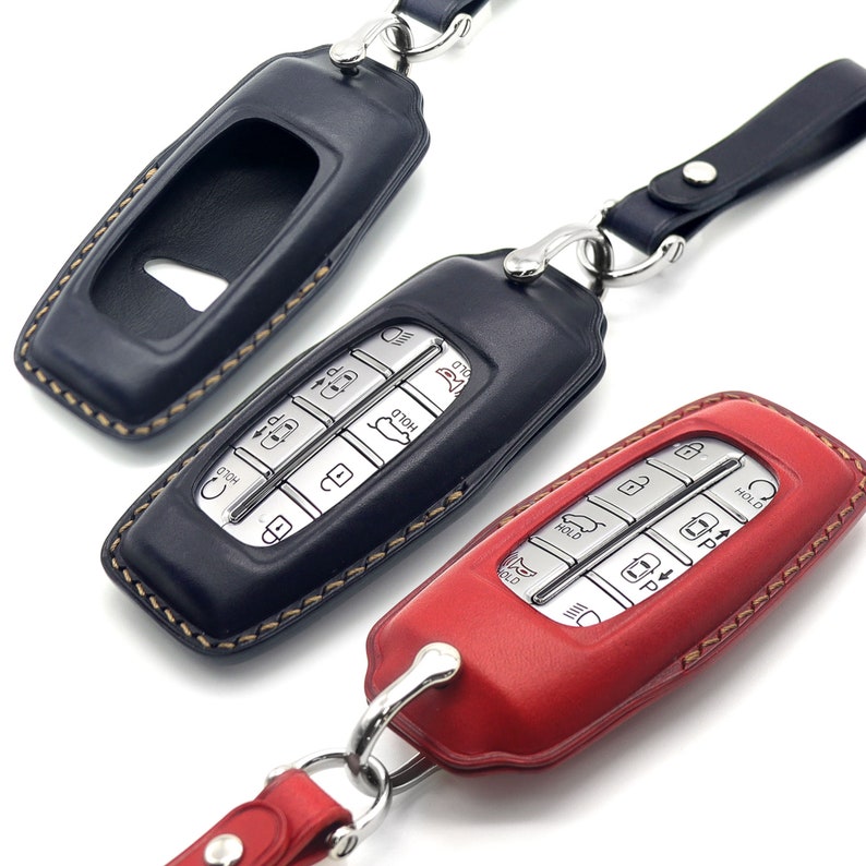 May include: Three leather key fobs with keychains. The key fobs are black, red, and brown. The black key fob has a silver key with buttons. The red key fob has a silver key with buttons. The brown key fob has a keyhole.