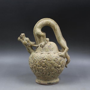 May include: A ceramic teapot with a dragon handle and spout. The teapot is decorated with a green glaze and has a detailed design of clouds and waves.